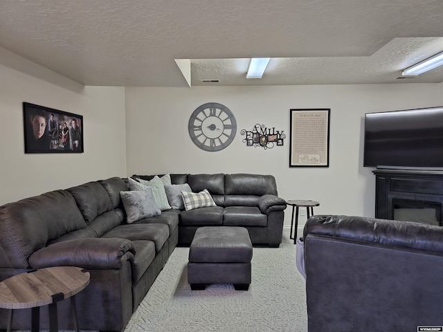 carpeted living area with a glass covered fireplace and a textured ceiling