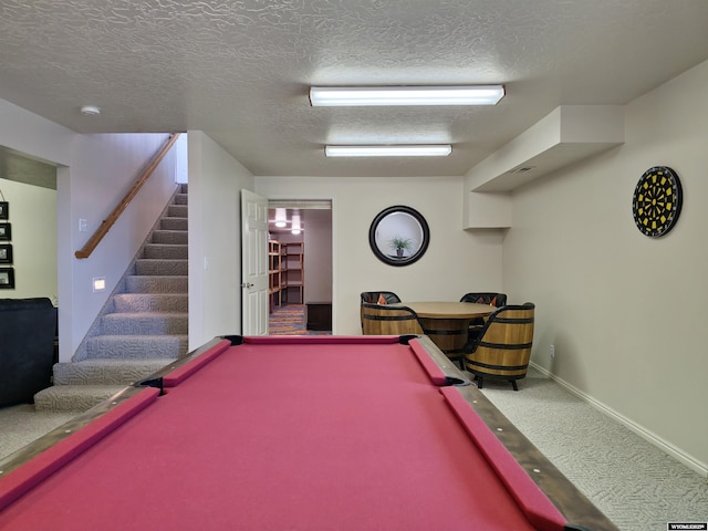 recreation room featuring baseboards, carpet, and a textured ceiling