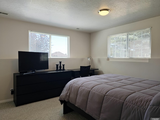 bedroom with visible vents, baseboards, light colored carpet, and a textured ceiling