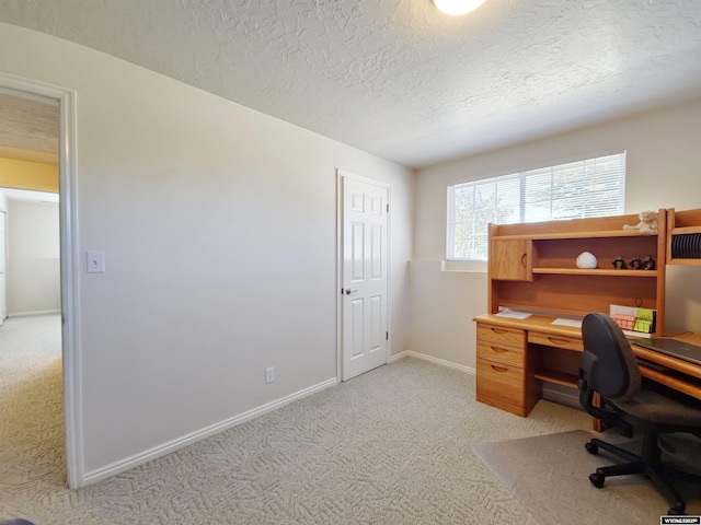 office space with a textured ceiling, baseboards, and light carpet