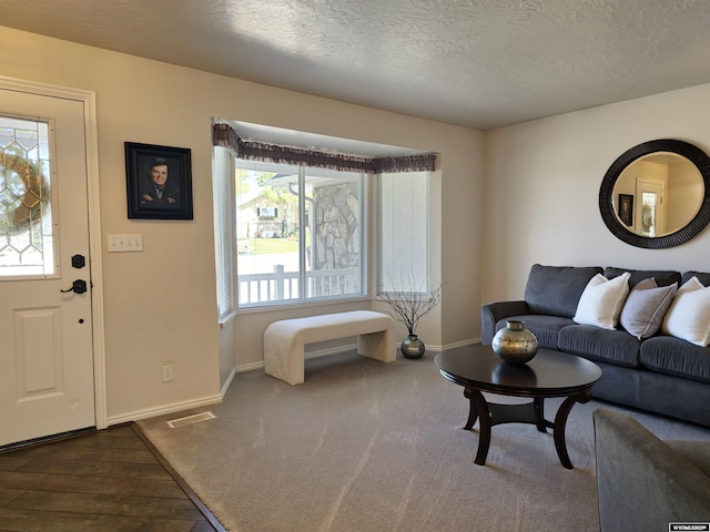 living area featuring visible vents, a textured ceiling, baseboards, and dark wood-style flooring