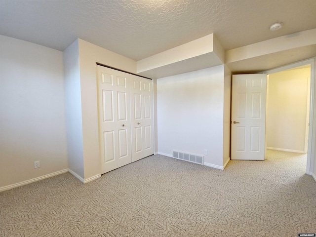 unfurnished bedroom featuring visible vents, baseboards, carpet flooring, a closet, and a textured ceiling