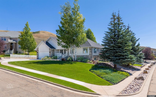 view of front of property featuring a garage, stone siding, a front yard, and fence