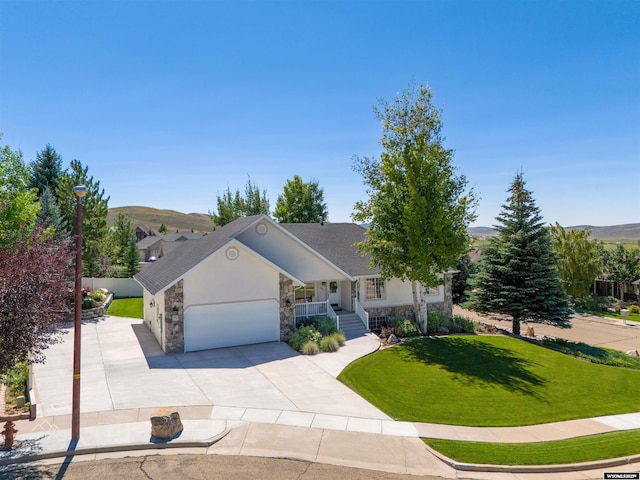 ranch-style home with a front lawn, stone siding, covered porch, concrete driveway, and an attached garage