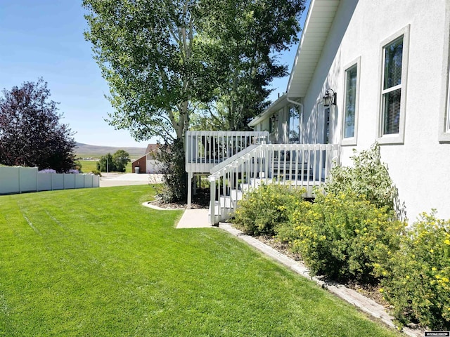 view of yard with a deck, stairs, and fence