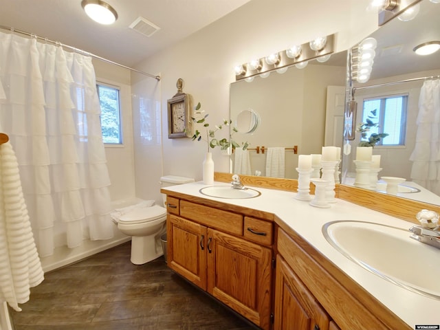 bathroom featuring double vanity, toilet, visible vents, and a sink