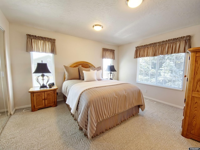 bedroom with visible vents, baseboards, light colored carpet, and a textured ceiling