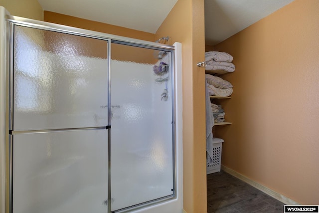 bathroom with a stall shower, baseboards, and wood finished floors