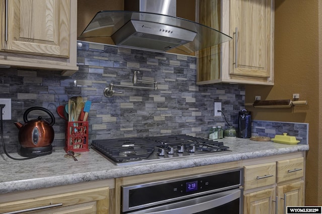 kitchen with decorative backsplash, extractor fan, appliances with stainless steel finishes, and light brown cabinets