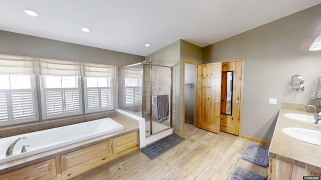 bathroom featuring a sink, wood finished floors, a garden tub, and a stall shower