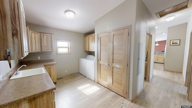 washroom with baseboards, light wood finished floors, cabinet space, a sink, and washer and dryer