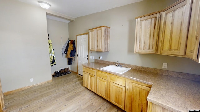 kitchen featuring light brown cabinets, baseboards, light wood-style flooring, a sink, and light countertops