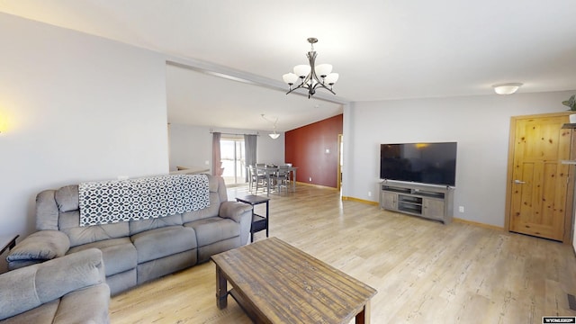 living area featuring baseboards, lofted ceiling, light wood-style floors, and an inviting chandelier