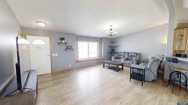 living room featuring a chandelier, baseboards, and light wood-style floors