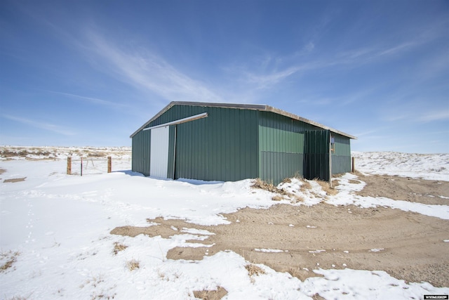 snow covered structure with an outdoor structure and a pole building