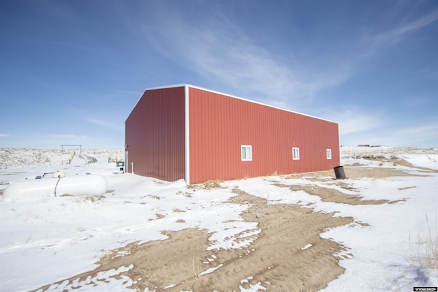 snow covered structure featuring an outbuilding