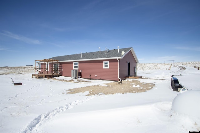 snow covered house featuring a wooden deck and cooling unit