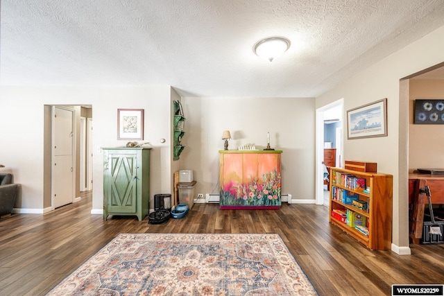 sitting room featuring a baseboard radiator, a textured ceiling, baseboards, and wood finished floors