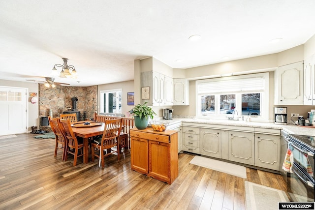 kitchen featuring range with two ovens, light wood-type flooring, a wood stove, and light countertops