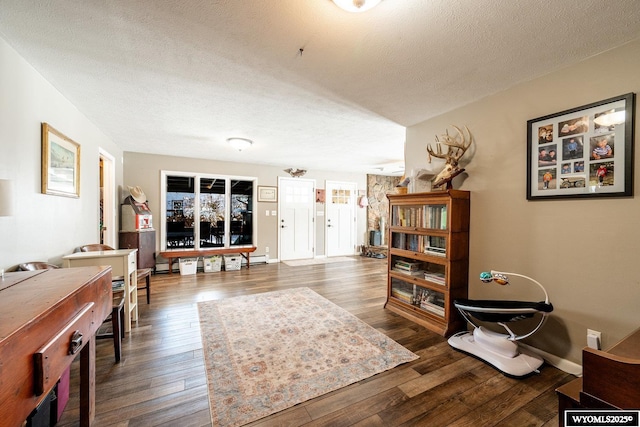 living room featuring baseboards, dark wood-style flooring, and a textured ceiling