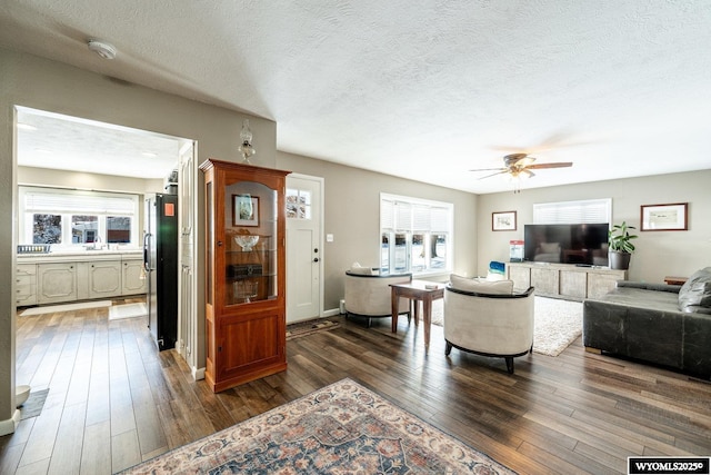 living area featuring dark wood finished floors, a textured ceiling, and ceiling fan