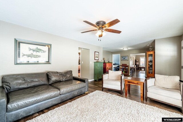 living room featuring baseboards, ceiling fan, and wood finished floors