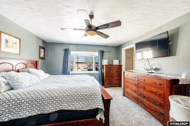 bedroom with a textured ceiling, a ceiling fan, and light carpet