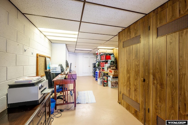 finished basement featuring concrete block wall and a paneled ceiling