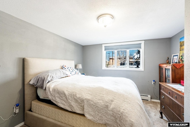 bedroom featuring a baseboard heating unit, light colored carpet, baseboards, and a textured ceiling