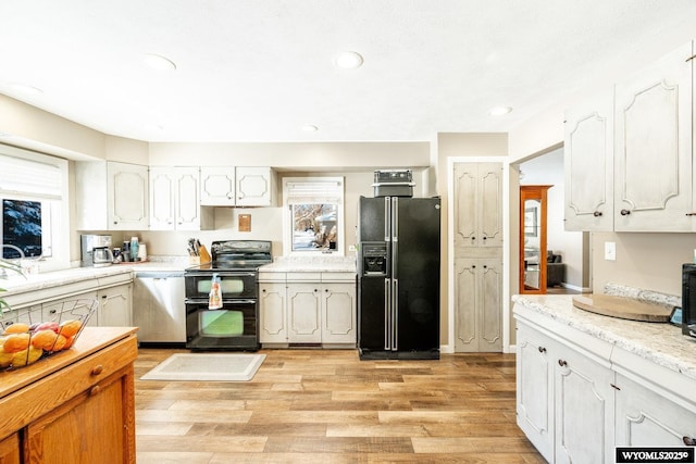 kitchen with recessed lighting, black appliances, light countertops, white cabinetry, and light wood-type flooring