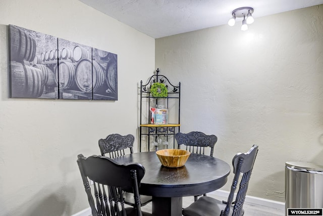 dining area with baseboards and a textured wall