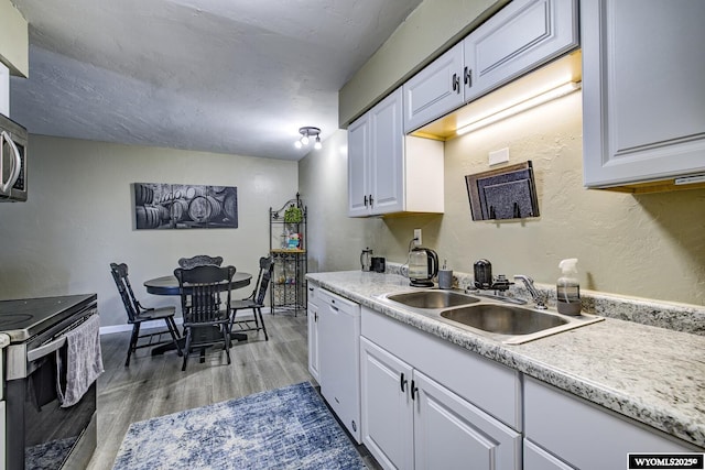 kitchen with a sink, range with electric cooktop, white cabinets, and white dishwasher