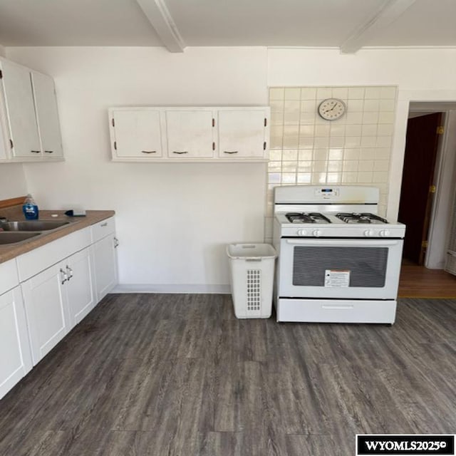 kitchen featuring tasteful backsplash, gas range gas stove, dark wood finished floors, white cabinets, and a sink