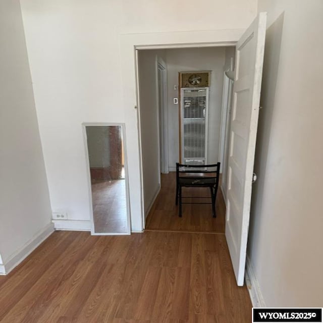 corridor with baseboards and wood finished floors