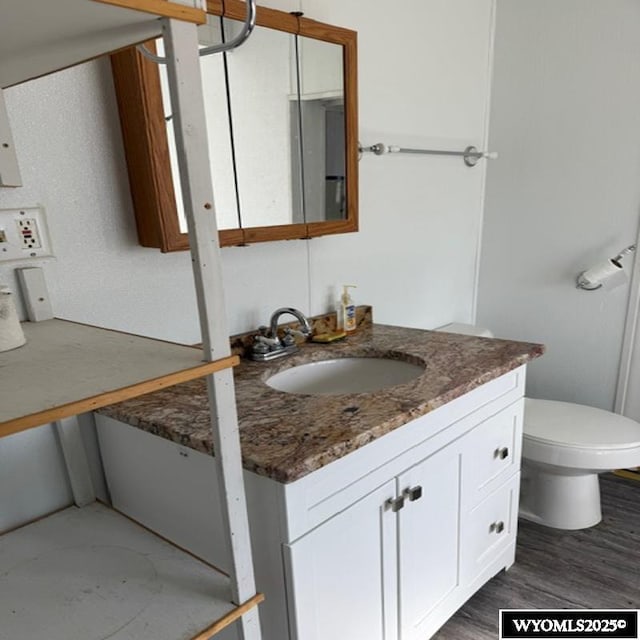 bathroom with toilet, wood finished floors, and vanity