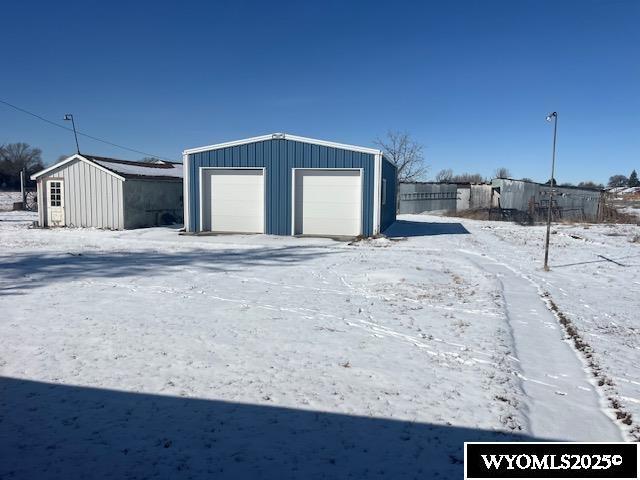 snow covered garage featuring a detached garage