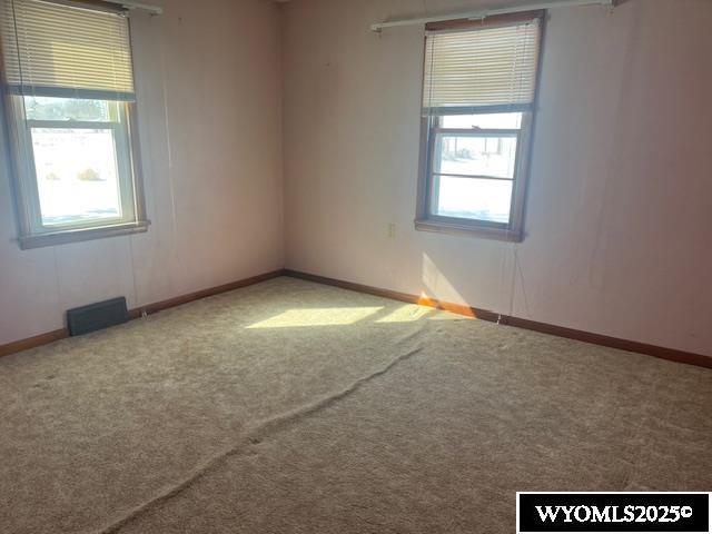 carpeted empty room featuring visible vents and baseboards