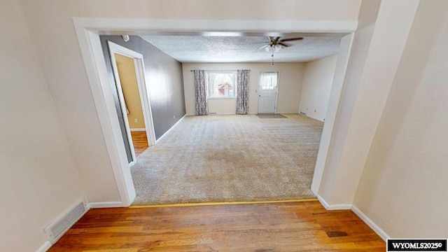 carpeted spare room featuring visible vents, a textured ceiling, and baseboards