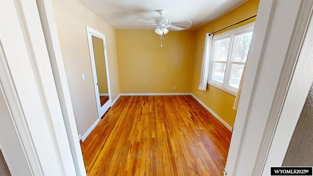 spare room featuring ceiling fan, baseboards, and wood finished floors