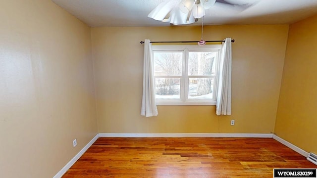 unfurnished room with wood finished floors, baseboards, and ceiling fan