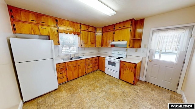 kitchen featuring white appliances, brown cabinets, and a sink