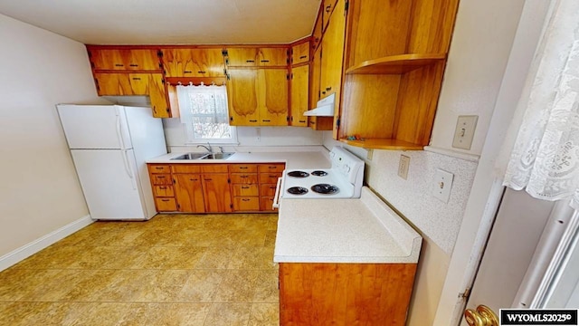 kitchen with ventilation hood, brown cabinetry, freestanding refrigerator, a sink, and electric range oven