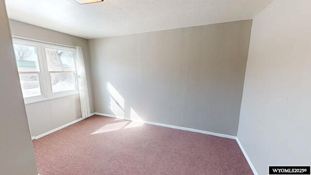 carpeted empty room featuring baseboards