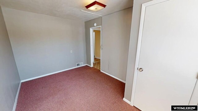 carpeted spare room featuring visible vents and baseboards