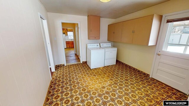 clothes washing area with cabinet space, washer and dryer, and tile patterned floors