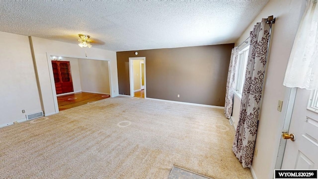 unfurnished room with visible vents, carpet flooring, a textured ceiling, and baseboards