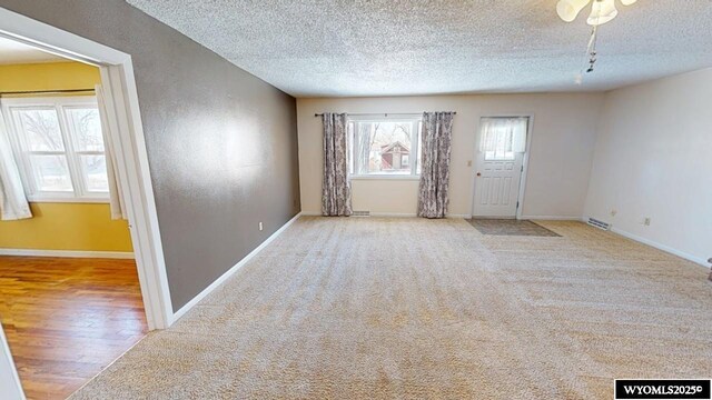 carpeted empty room with a textured ceiling and baseboards