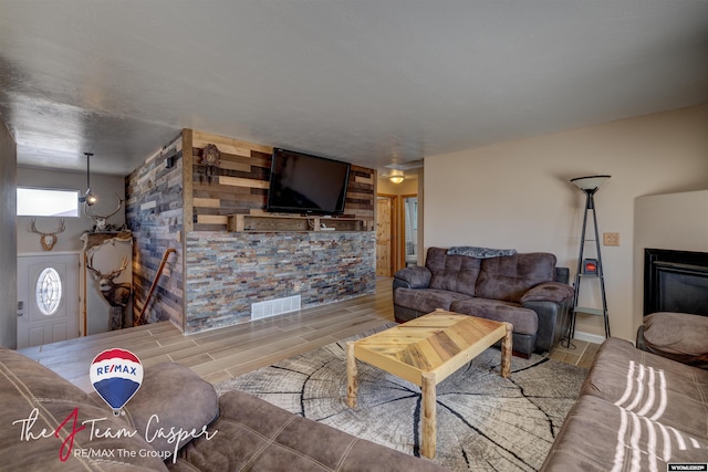 living area with wood finished floors, a fireplace, and visible vents