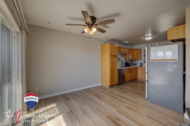 kitchen with baseboards, wood finish floors, a sink, stainless steel appliances, and light countertops