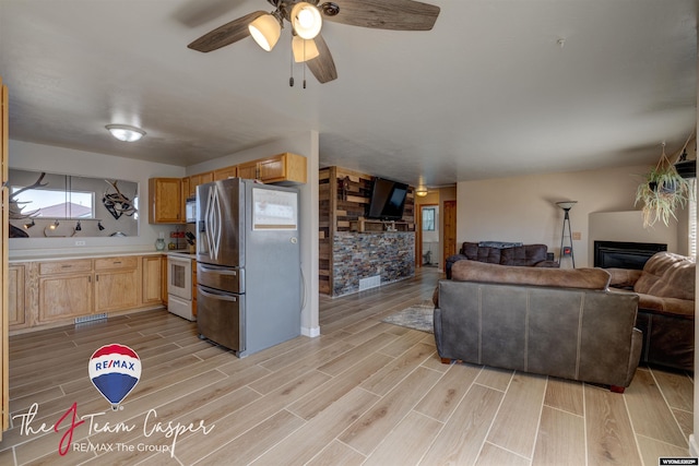 living room with ceiling fan, a glass covered fireplace, and wood tiled floor